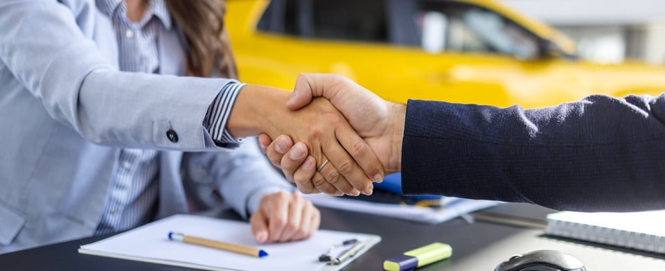Two people shaking hands at a car dealership